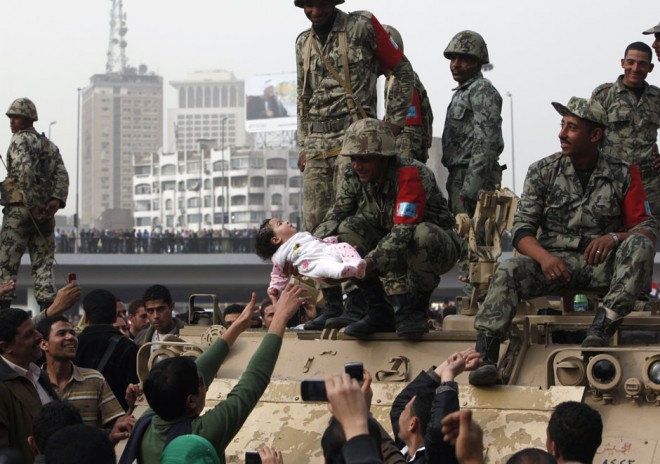 A protester reaches out as a soldier holds a child during a demonstration in Cairo